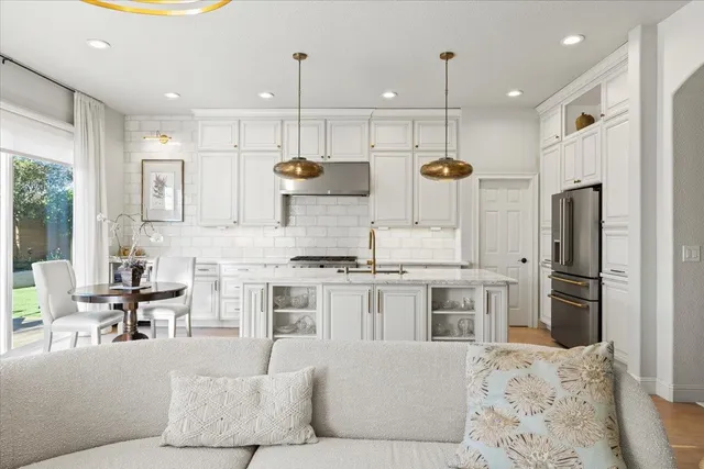 a kitchen with stainless steel appliances kitchen island granite countertop a refrigerator a stove a sink a dining table and chairs with wooden floor