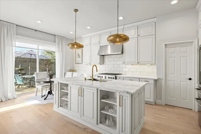 a kitchen with a stove a window and chairs