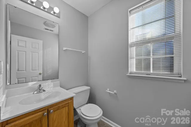 a bathroom with a granite countertop sink toilet a mirror and a window