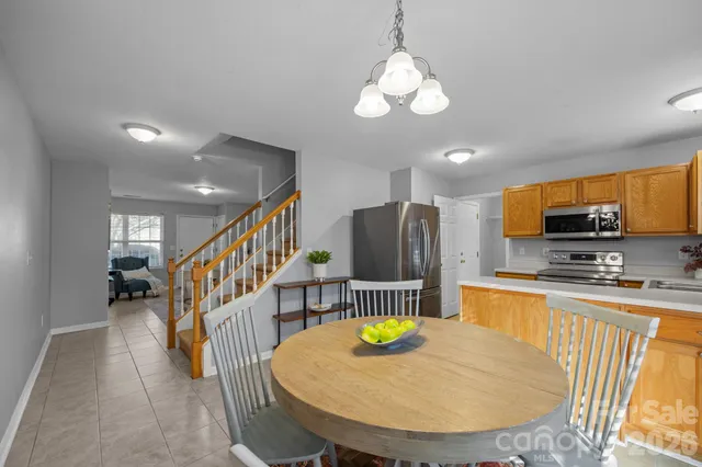 a kitchen with stainless steel appliances granite countertop a sink a stove a dining table and chairs