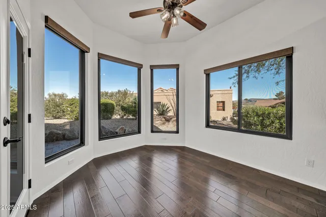a view of an empty room with window and wooden floor