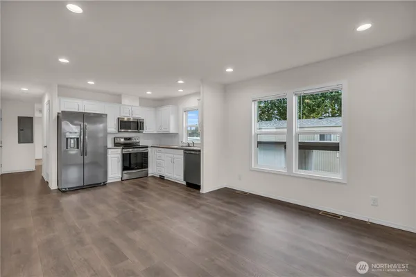 a large kitchen with stainless steel appliances granite countertop a large counter top and a wooden floor
