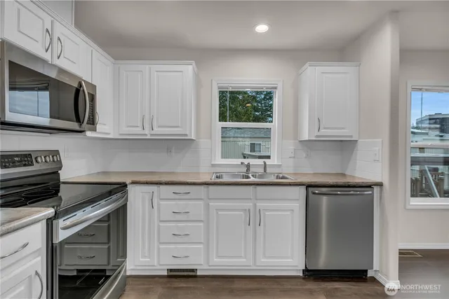 a kitchen with stainless steel appliances granite countertop a stove a sink and a microwave