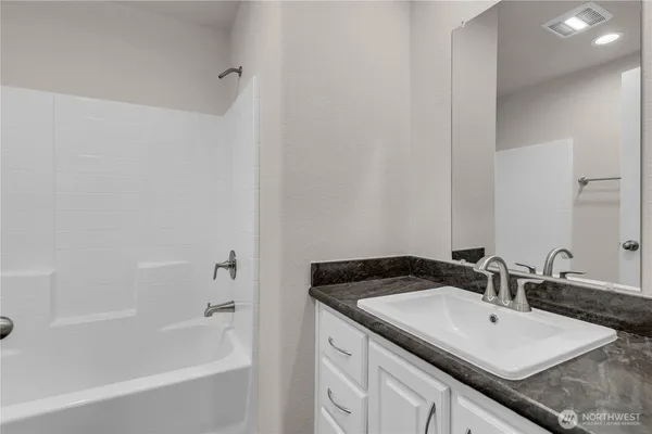 a bathroom with a granite countertop sink and a bathtub