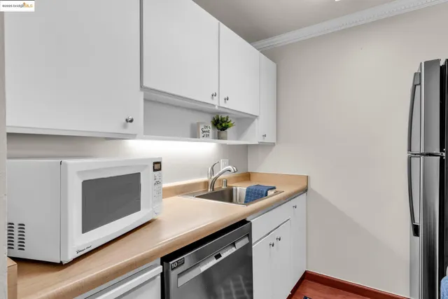 a kitchen with cabinets stainless steel appliances a sink and wooden floor