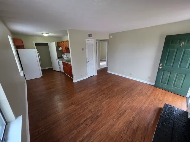 a view of an empty room with wooden floor and a sink