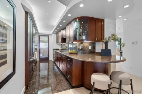 a kitchen with stainless steel appliances kitchen island granite countertop a table chairs and a refrigerator
