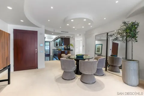 a dining room with furniture a potted plant and a kitchen view
