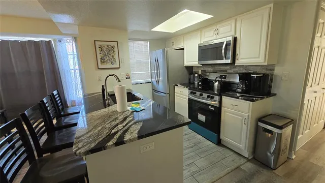 a kitchen with stainless steel appliances granite countertop a refrigerator a stove top oven a sink and dishwasher