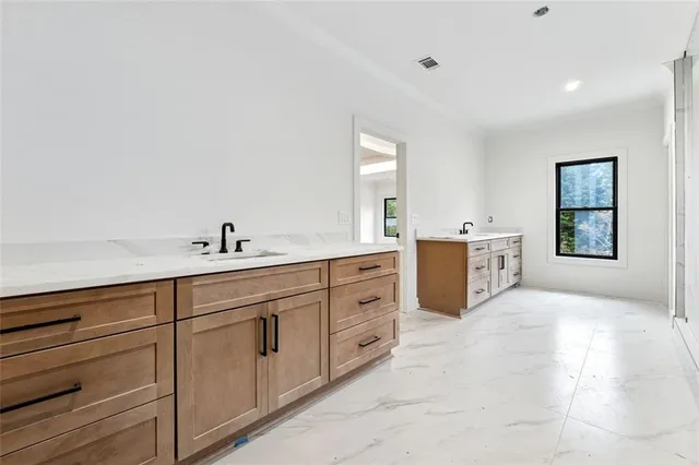 a spacious bathroom with double vanity sink a two mirror a window and a bathtub