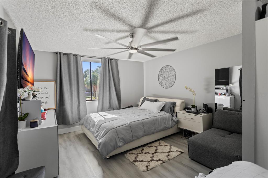 22940 Oxford Place, Unit C Boca Raton, FL 33433 - Photo 24 of 60 a bedroom with a bed couch chandelier and a window