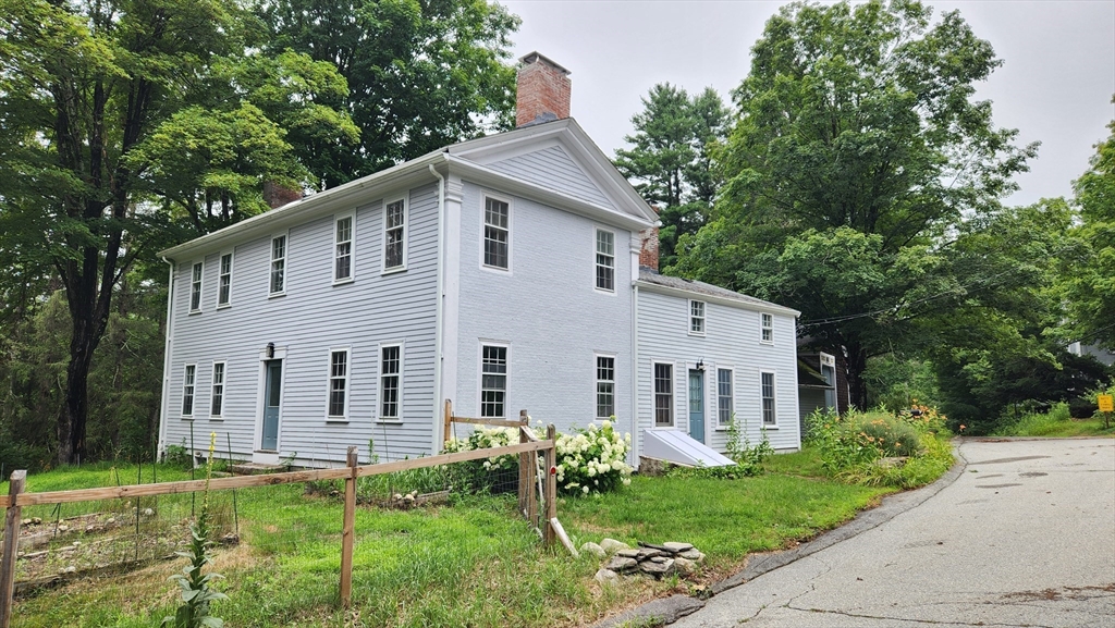 a view of a white house with a yard and plants