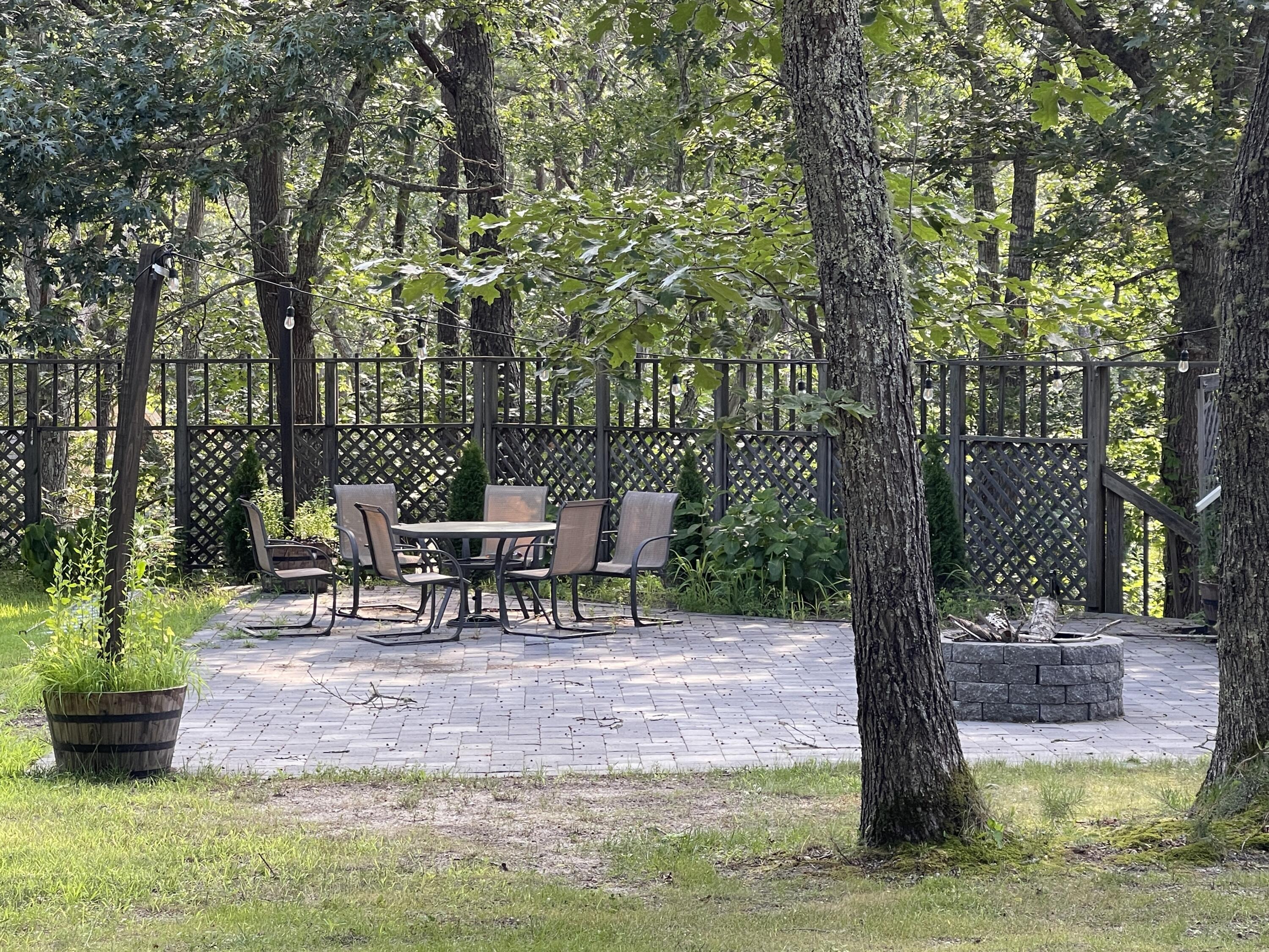 115 Pine Needle Road Wellfleet, MA 02667 - Photo 5 of 37 a view of a patio with table and chairs potted plants and large tree