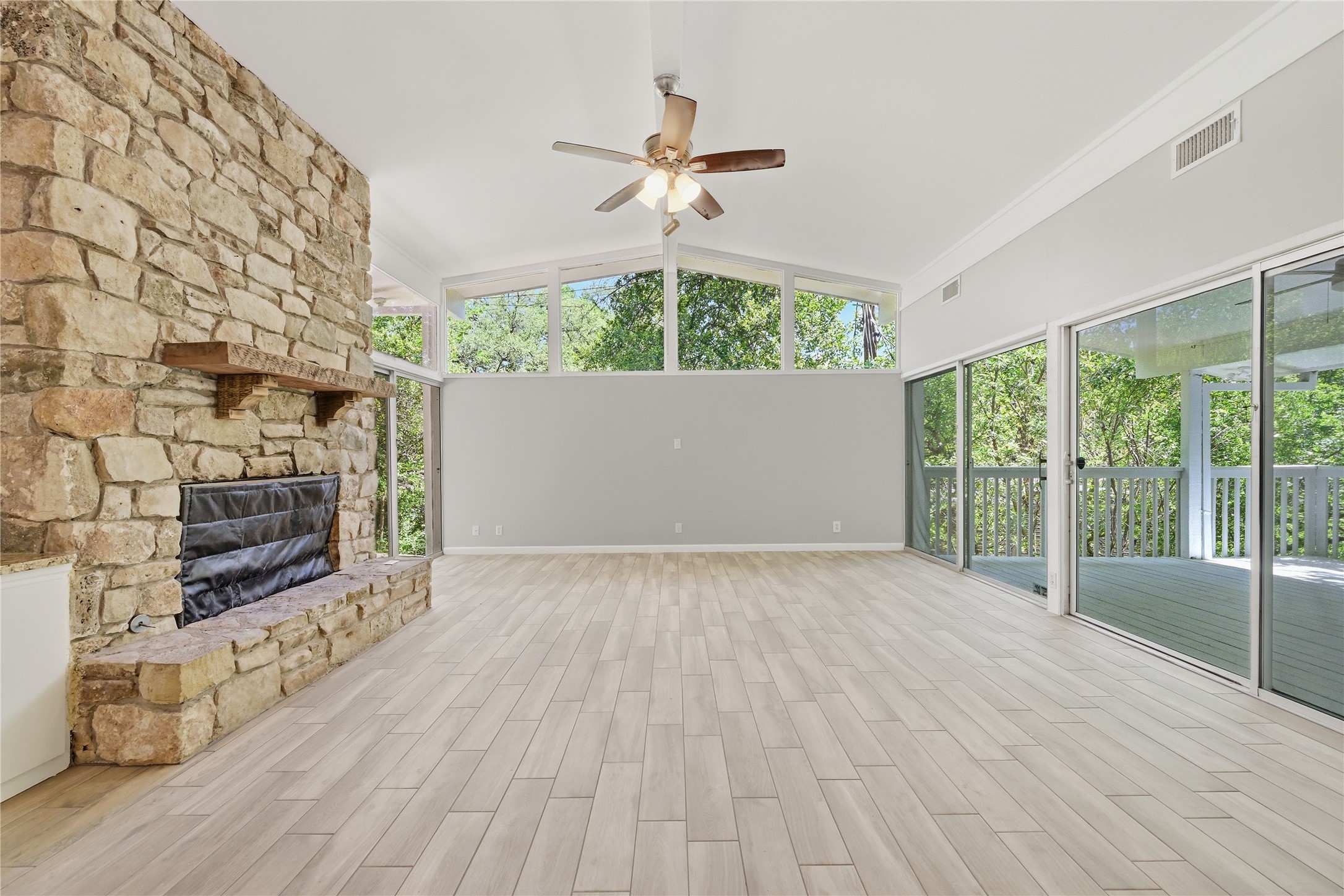 7 Hull Circle Austin, TX 78746 - Photo 5 of 17 A striking stone fireplace anchors this living space, offering warmth and a connection to the expansive outdoor decking and verdant views.