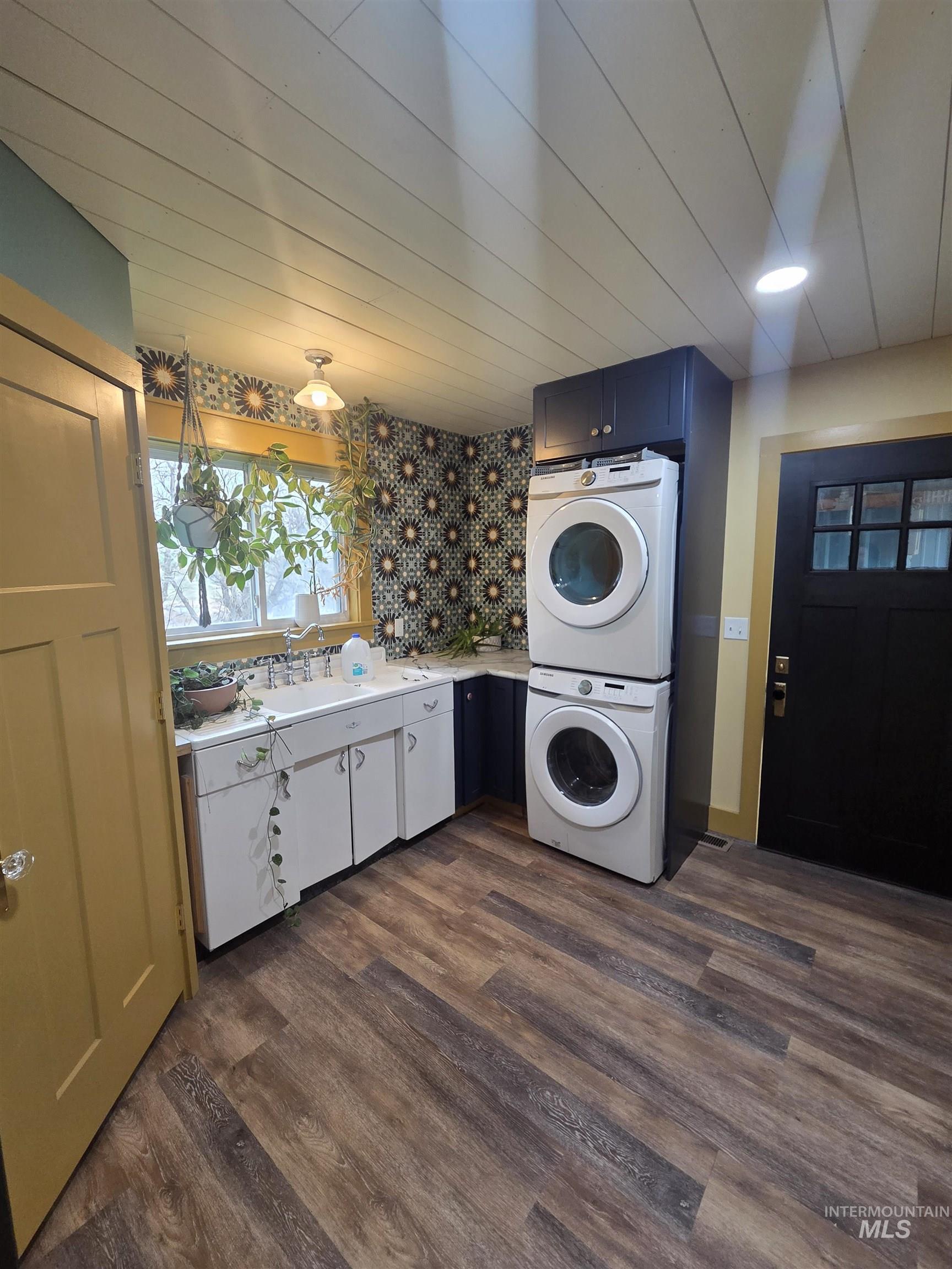 870 Dutch Flat Road Pomeroy, WA 99347 - Photo 9 of 33 Laundry area with stacked washing machine and dryer, dark wood-style floors, and cabinet space