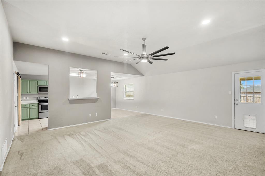 10620 Granada Drive Waco, TX 76708 - Photo 5 of 38 Vaulted ceiling with recessed lighting and a ceiling fan, a pass-through window to the kitchen featuring green cabinetry, and wood-finish flooring