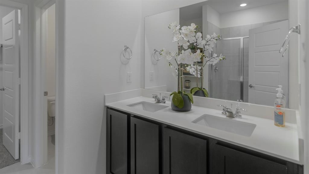 410 Range Road Caddo Mills, TX 75135 - Photo 12 of 19 Dual vanity with undermount sinks, white countertop, dark wood-finish cabinetry, and a large wall-mounted mirror