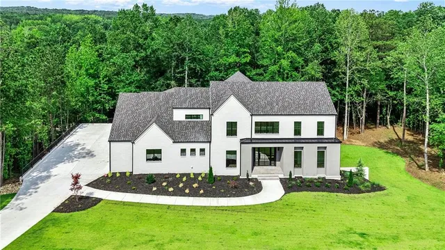 an aerial view of residential house with yard and trees in the background