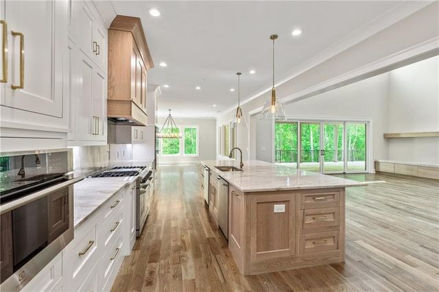 a view of a hallway with wooden floor and a bathroom