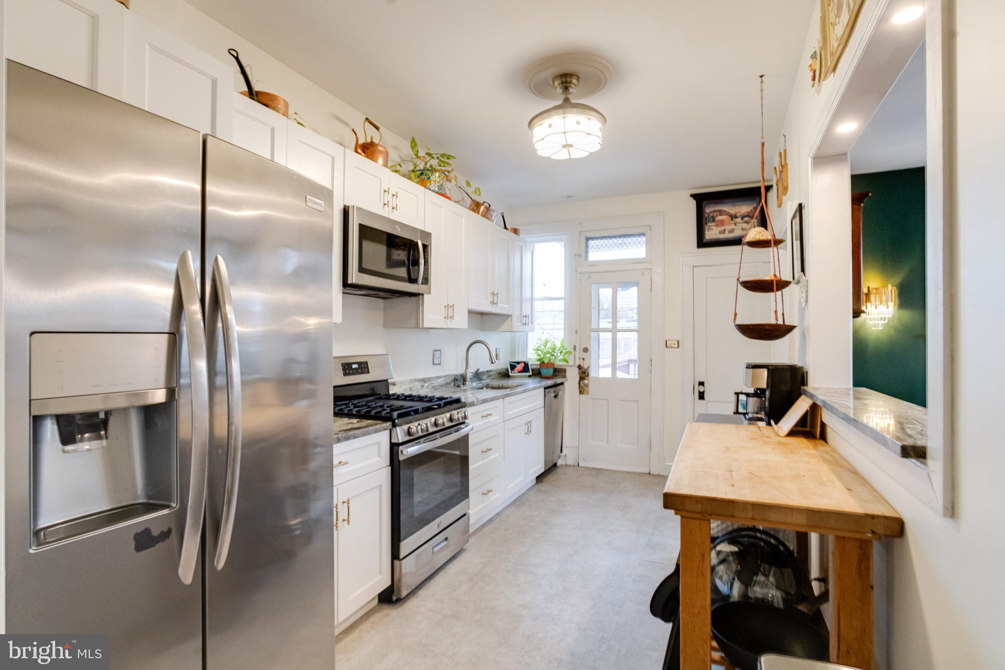 3901 Keswick Road Baltimore, MD 21211 - Photo 26 of 87 a kitchen with stainless steel appliances kitchen island granite countertop a refrigerator a stove and a sink with wooden floor