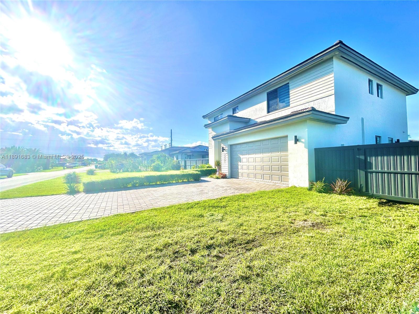 a view of a house with a yard and a large tree
