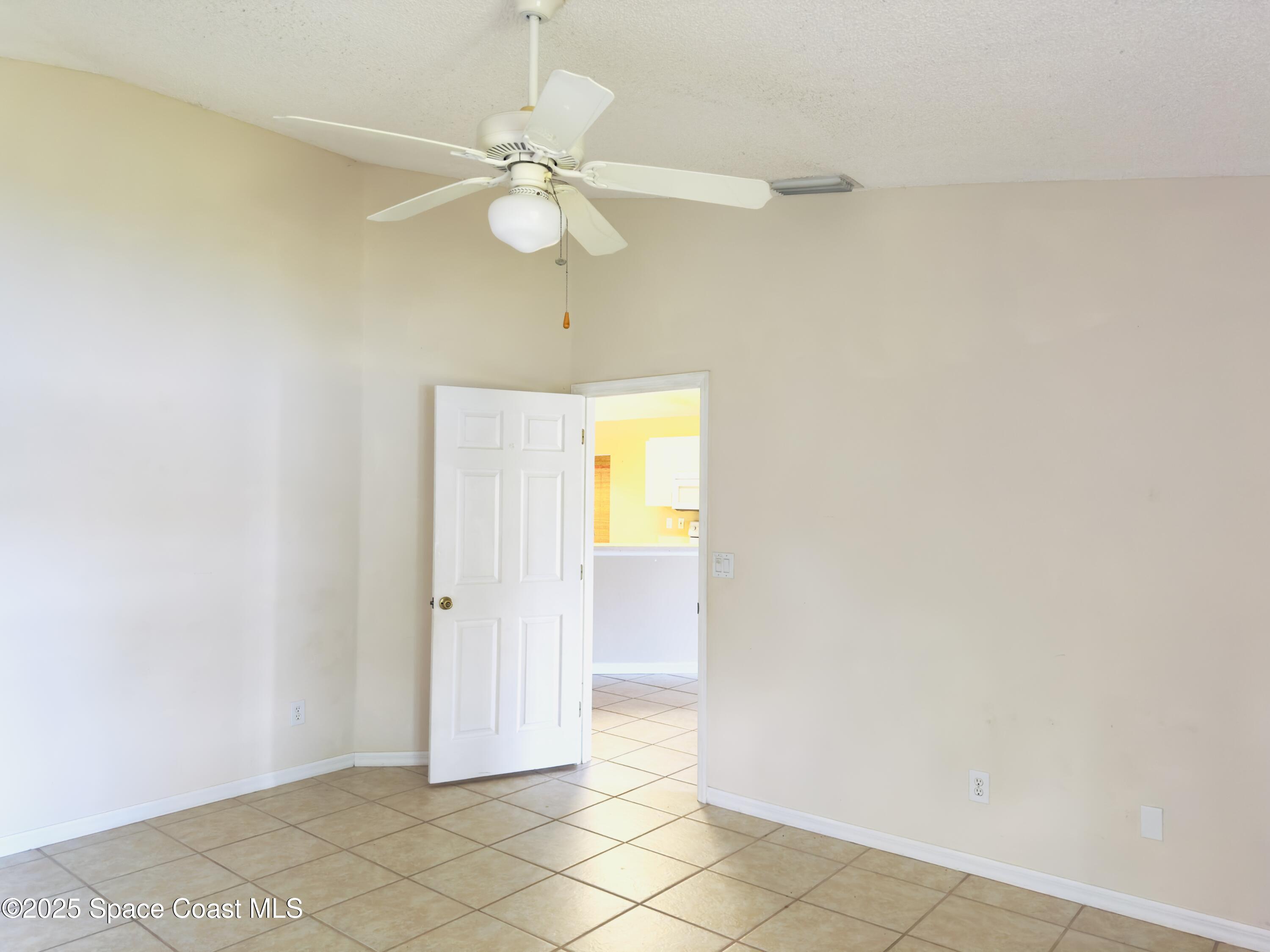 4691 Manchester Drive Rockledge, FL 32955 - Photo 6 of 6 an empty room with wooden floor and fan