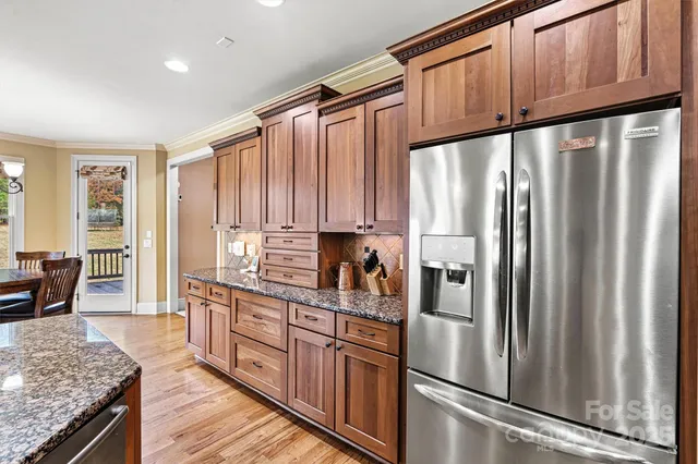 a kitchen with stainless steel appliances granite countertop a refrigerator a sink dishwasher a stove and white countertops with wooden floor