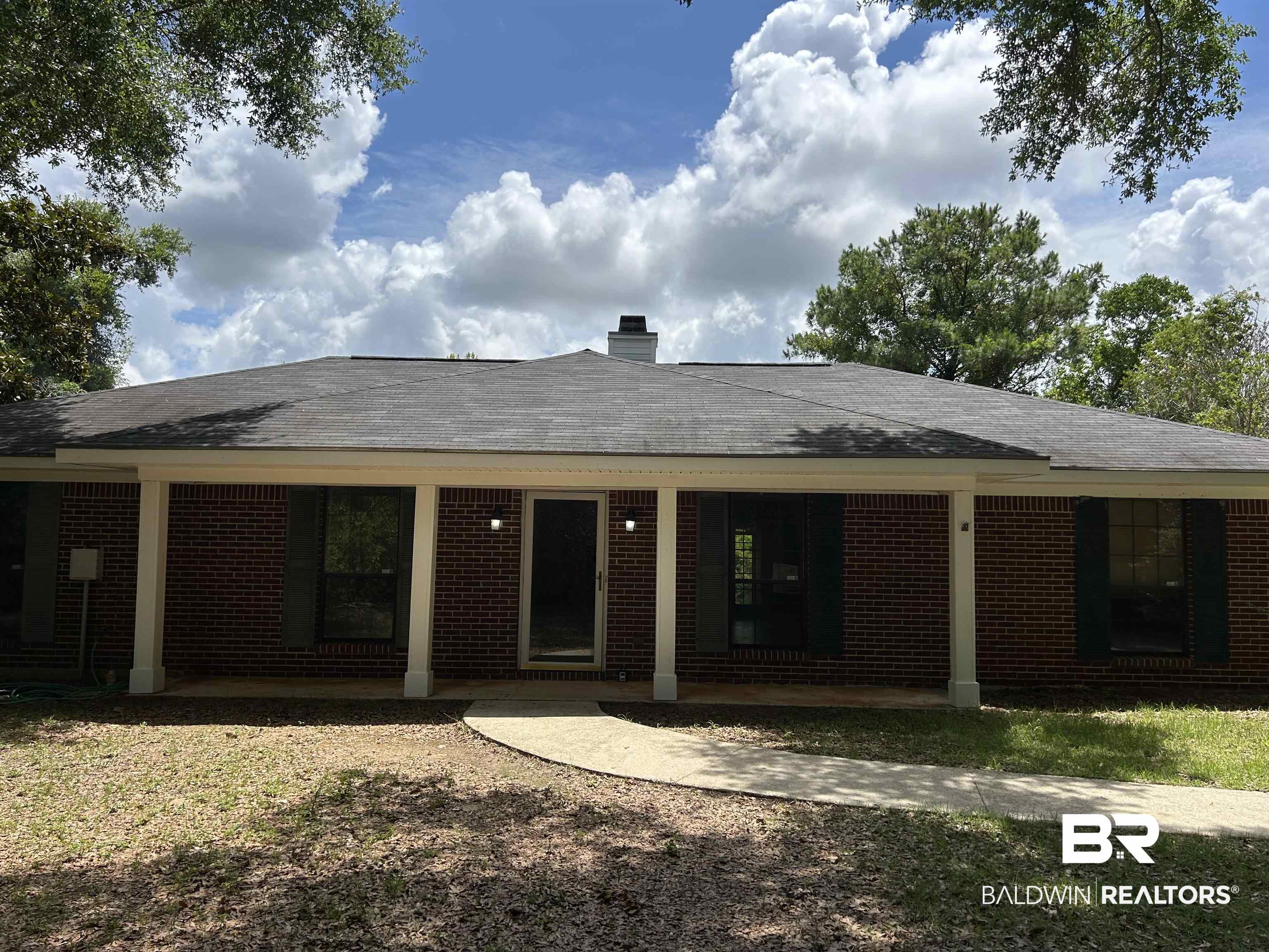15602 Wrangler Road Summerdale, AL 36580 - Photo 2 of 14 Front of property featuring brick siding, a chimney, a shingled roof, and a patio area