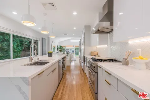 a kitchen with a stove a sink a refrigerator and blue cabinets with wooden floor
