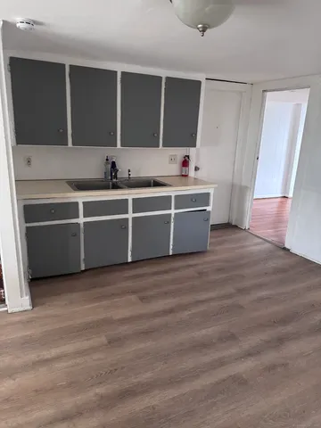 a view of a kitchen with stainless steel appliances wooden floor and a sink