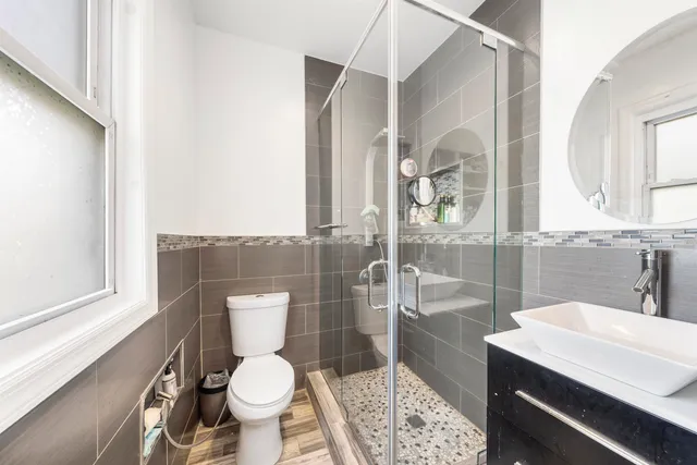 a bathroom with a sink a toilet a mirror and shower