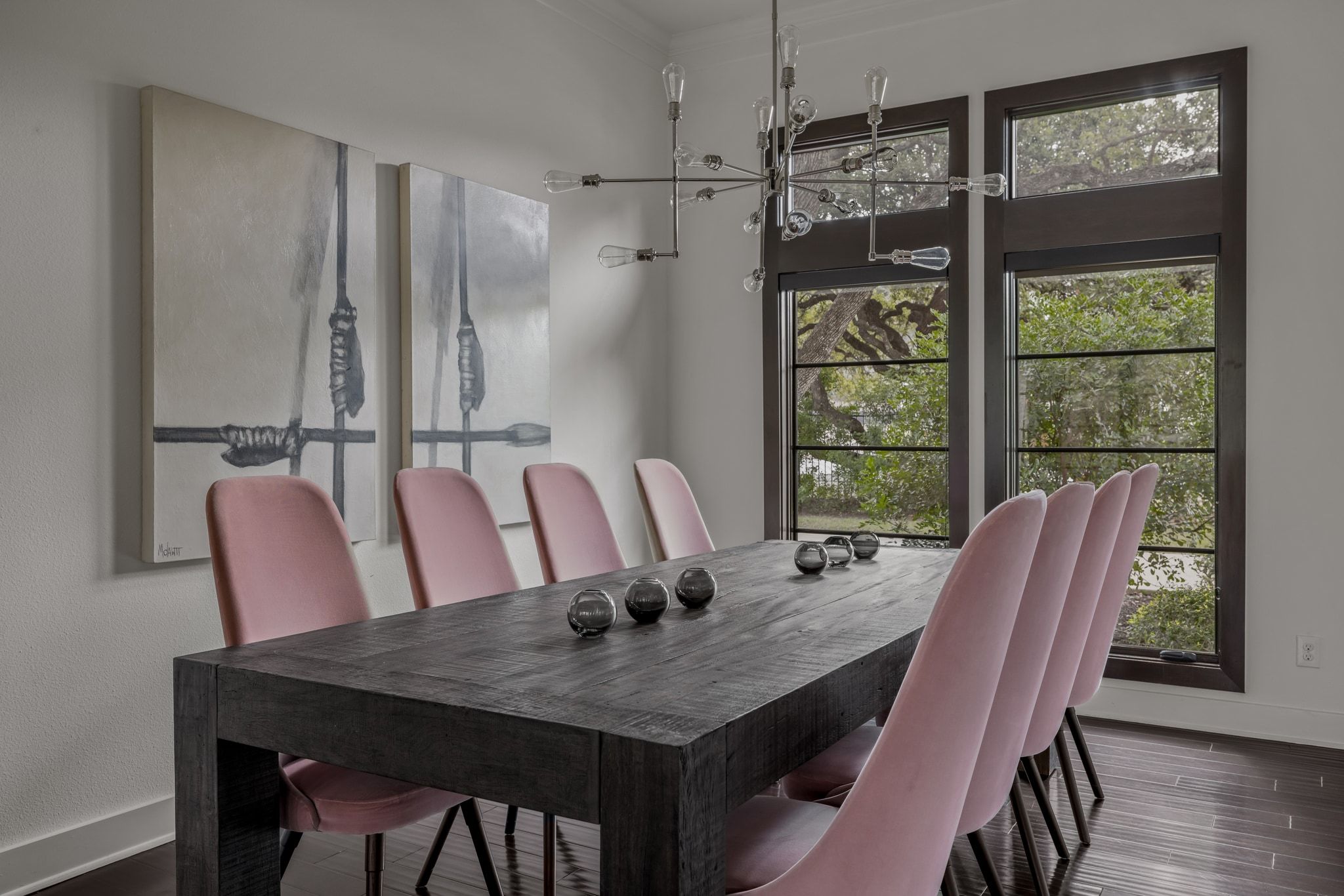 4720 Rockcliff Road, Unit 1 Austin, TX 78746 - Photo 20 of 39 A striking modern chandelier illuminates a sophisticated dining space with rich hardwood flooring and tall windows.