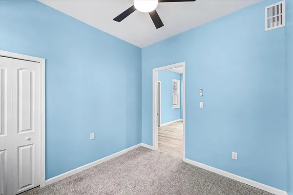 an empty room with ceiling fan and window