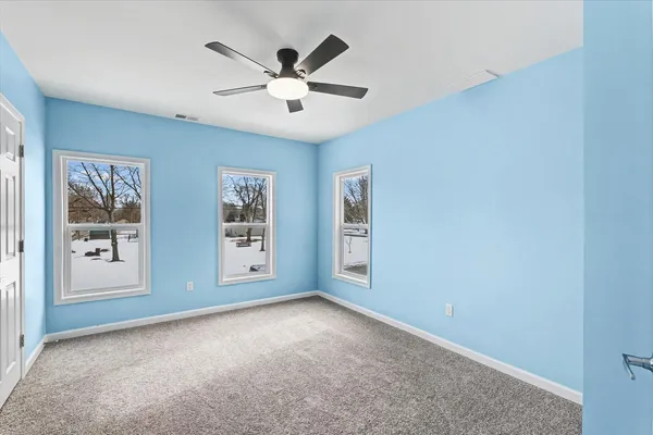 an empty room with windows and fan