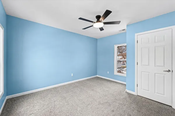 an empty room with windows and fan