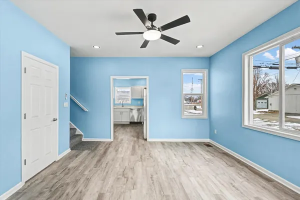 a view of empty room with wooden floor and fan