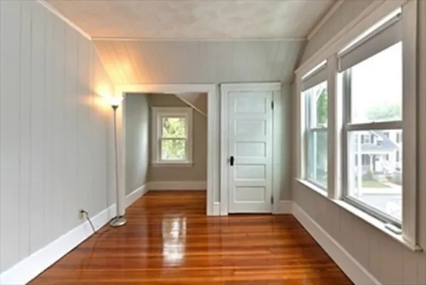 a view of an empty room with window and wooden floor