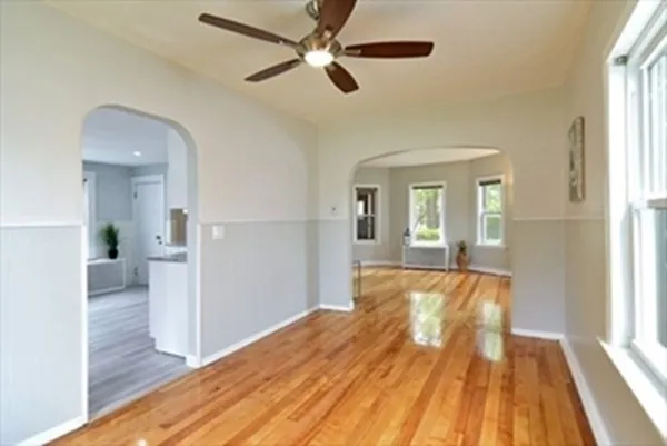 a view of empty room with wooden floor and fan