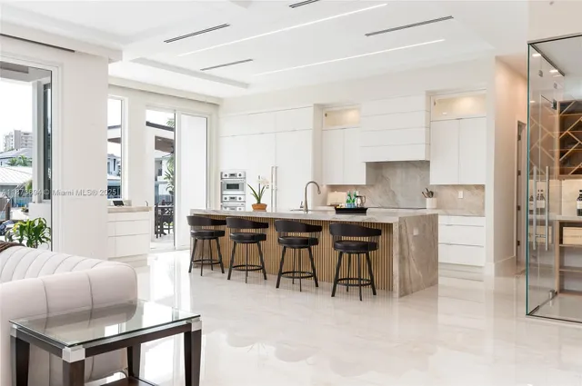 a open dining room with stainless steel appliances kitchen island granite countertop a table chairs and a refrigerator