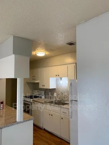 a kitchen with granite countertop a refrigerator and a stove top oven