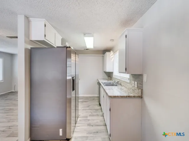 a kitchen with stainless steel appliances granite countertop a refrigerator and a sink