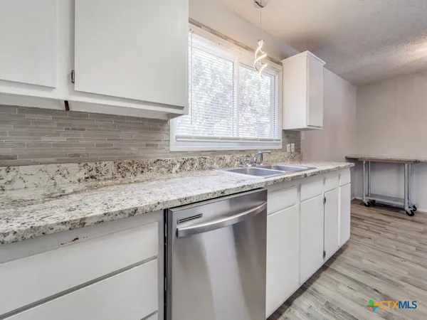 a kitchen with granite countertop cabinets sink and window