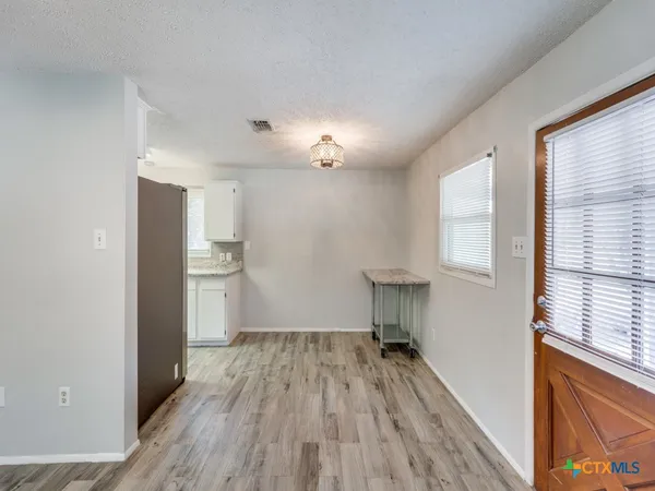 a view of a room with wooden floor a ceiling fan and windows