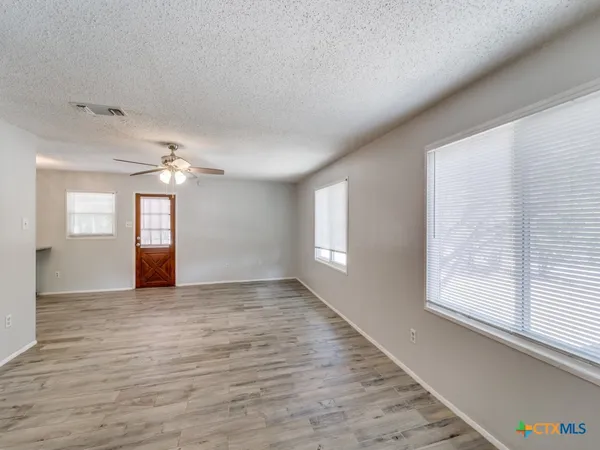 an empty room with wooden floor and windows