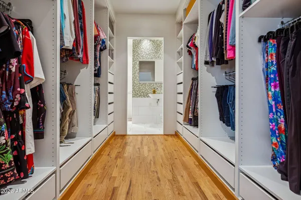 a view of walk in closet with clothes and shoes