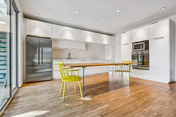 a room with stainless steel appliances kitchen island granite countertop a table chairs and a refrigerator