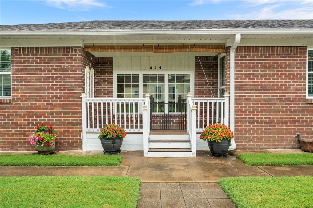 Brick exterior with a covered entry, white porch railings, and a concrete walkway