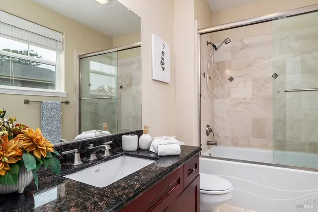 a bathroom with a granite countertop tub sink toilet and mirror