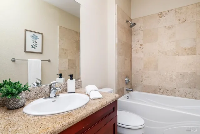 a bathroom with a granite countertop sink mirror toilet and bathtub