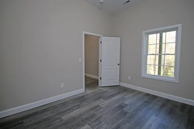 a view of an empty room with wooden floor and closet